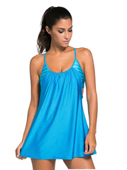 A woman wearing a blue tankini swimsuit with a gathered neckline and spaghetti straps.