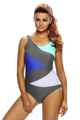 A woman wearing a multicolor teddy bikini with a tankini design, featuring bold geometric patterns in blue, green, grey, and white.