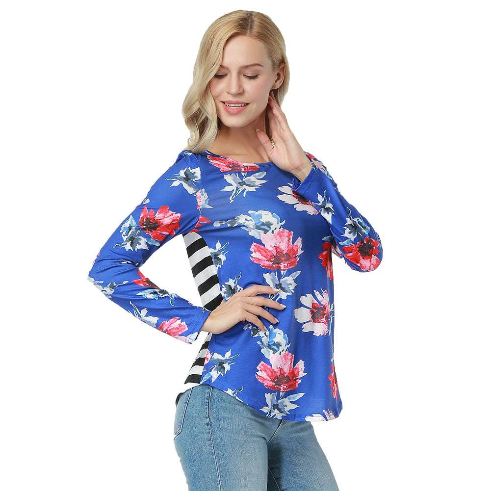 A woman wearing a blue long-sleeved top with a combination of bold stripes on the sleeves and a vibrant floral print on the front.