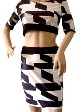 A mannequin showcasing a black and white abstract geometric patterned bodycon dress.