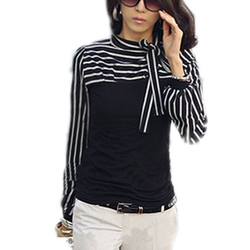 A woman wearing a black stripe shirt with a bowknot front, paired with sunglasses and beige pants.