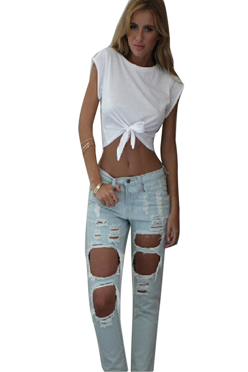 A female model wearing a white sleeveless cotton crop top with a bow tie at the belly button and blue distressed jeans.