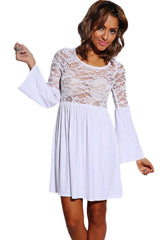 A woman wearing a white mini dress with full sleeves and a floral mesh see-through design.