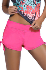 A close-up image of a woman wearing pink ruched side swimsuit bottoms with a floral patterned top.