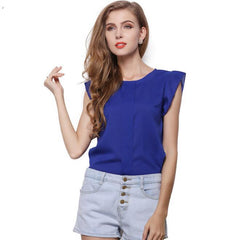 A woman wearing a blue scoop neckline shirt with cap sleeves and a form-fitting design, paired with denim shorts.